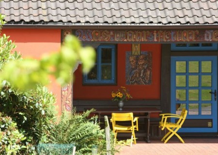 Bunte Idylle im Grünen: Das Böckstiegelhaus besticht durch rote Fassade mit blauen Fensterläden, Copyright: © Peter-August-Böckstiegel-Stiftung