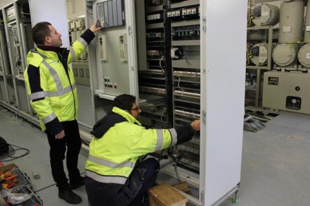 Kornel Witte (rechts) von der Firma Siemens und Hendrik Lohmann von den Stadtwerken Bielefeld kontrollieren die neue Steuer- und Leittechnik. Im Hintergrund sieht man die 110.000 Volt-Schaltanlage im Umspannwerk Kraftwerk.