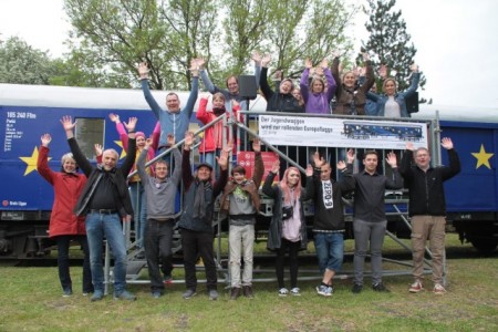 Begeistert für die Demokratie - Die Organisatoren der U18-Europawahl freuen sich gemeinsam mit Gästen und „Jungwählern“ vor dem als Europaflagge lackierten Jugendwaggon an der Bahnmeisterei in Farmbeck, Foto: Ilja Nowodworski