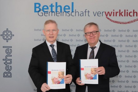 Pastor Ulrich Pohl (r.) und Dr. Rainer Norden mit dem aktuellen BethelJahresbericht 2018/2019. (Foto: Bethel) 