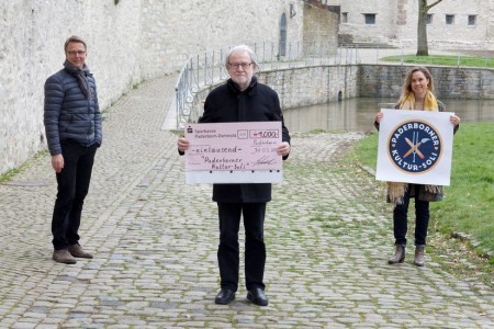 Der 1. Vorsitzende des Freundeskreis der Städtischen Museen und Galerien Paderborn, Josef Hackfort, überreicht einen symbolischen Scheck an die Initiatoren des „Paderborner Kultur-Soli“ Markus Runte und Julia Ures. Olaf Menne, der dritte des Projektes, fehlt auf dem Foto. Foto: © Harald Morsch