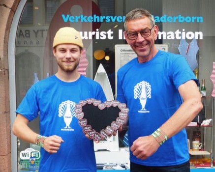 Tobias Schmidt (links) und Karl Heinz Schäfer von der Tourist Information Paderborn präsentieren die diesjährigen Libori-Artikel. Foto: © Stadt Paderborn
