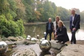 Wasserperlen, die über dem Wasser schweben, aber doch fest verankert sind: Bernd Winkler, Leiter des Fachbereichs Grünflächen, Daniela Toman, Larissa Lakämper (Vorsitzende und Vorstandsmitglied des Förderkreises Stadtpark-Botanischer Garten) und Bürgermeister Henning Schulz stellen die neue Skulptur am Stadtparkteich vor.