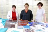 Shopprodukte, Plakate und eine Fahne des Katholikentags in Münster übergab die Vorsitzende des Katholikentags-Trägervereins, Anne Hakenes (Mitte) an Dr. Barbara Rommé, Direktorin des Stadtmuseums, und Dr. Edda Baußmann, zuständig für Inventarisierungen (von links). (Foto: Katholikentag / Katzenberger)