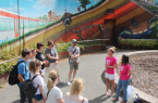 Während der neuen Kiez-Tour geben die beiden Stadtführerinnen von Bielefeld Marketing Janine Vetter (l.) und Yvonne Bock (in pinken Bielefeld-Shirts) Informationen zum auffälligen Graffiti an der Stadtbahn-Unterführung zur Rudolf-Oetker-Halle. Copyright: © Bielefeld Marketing GmbH