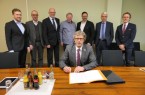 Unterzeichnung: Neben Bürgermeister Michael Jäcke (Mitte, sitzend) für die Stadt unterzeichneten alle Partner des „Bündnisses für Wohnen“ ein Memorandum (stehend von links): Eugen Pankratz (Wohnhaus Minden GmbH), Jochen Rogmann (Lebenshilfe e.V.), Christian Schultz (Diakonie Stiftung Salem GmbH), Thorsten Post (Haus & Grund e.V.), Beigeordneter Lars Bursian, Bernd Hausmann (Genossenschaft für Siedlungsbau und Wohnen Minden eG - GSW), Thorsten Bornemann (Mieterverein Minden und Umgebung e.V.).