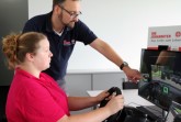 Björn Jockwig, Ausbildungsleiter der Johanniter in Lippe-Höxter, testet mit Mareike Bark am Fahrsimulator das Programm „Abgelenktes Fahren“ des UPS Road Code. Foto: Johanniter Unfallhilfe