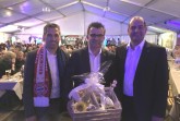 Über einen gut besuchten Volksbank-Moritzabend in Büren freuen sich Festredner Martin 
Hornberger (Mitte), Bankvorstand Thorsten Wolff (rechts) und Bürgermeister Burkhard Schwuchow 
(links), der den besonderen Fußballschal vom Festredner als Geschenk erhielt. Foto: Stadt Büren