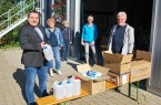 Landrat Dr. Axel Lehmann macht sich ein Bild von der Verteilung der Schutzmaterialien: Anke Stetza, Ute Model und Anja Krause (von links) von der Pflege- und Heimaufsicht haben zahlreiche Kisten gepackt. Karl-Heinz Bredenkamp holt das Material für den Lippischen Blinden- und Sehbehinderten-Verein ab. Foto: Kreis Lippe