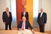 Im Beisein von Kreishandwerksmeister Mickel Biere, Bürgermeister Michael Dreier und Erzbischof Hans-Josef Becker (v.l.n.r.) trug sich Wirtschaftsminister Peter Altmaier (vorne) in das Goldene Buch der Stadt Paderborn ein.Foto: © Stadt Paderborn