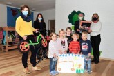 Bürgermeister Ernst-Wilhelm Vortmeyer übergibt eine Satteltasche an Katja Aufderheide (rechts). Die Kinder der evangelischen Kita Schwenningdorf haben mit Kitaleiterin Christine Limberg Fahrradbilder gemalt und zusammen mit den Eltern und Erzieherinnen 561 Kilometer erradelt. Rödinghausens Klimaschutzmanagerin Dr. Sarah Sierig (links) übergab der Kita ein neues Laufrad.