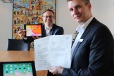 Bürgermeister Theo Mettenborg und Digitalisierungsbeauftragter für den 
Bereich Jugend, Alexander Löhner, freuen sich über die Förderzusage und testen das erste 
Tablet für die Schülerinnen und Schüler. Foto: Stadt Rheda - Wiedenbrück