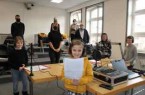 Schaffen Lichtmomente auf Distanz: (vorn v.l.) Charlotte (8), Jule (8), Emily (9) und Fabian (9) von der Katholischen Grundschule Stukenbrock produzieren vier weihnachtliche Radiobeiträge in der Volkshochschule Gütersloh. Unterstützt werden sie dabei von ihren Lehrern (hinten v.l.) Julius Büscher, Anja Schormann und Magdalena Frielinghaus sowie durch Dr. Mariella Gronenthal, stellvertretende Leiterin der Volkshochschule Gütersloh, und Medientrainer Manfred Nöger.Foto:Stadt Gütersloh