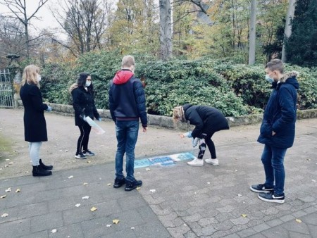 Schülerinnen und Schüler der Elly-Heuss-Knapp-Realschule erinnern mit Symbolen auf dem Pflaster in der Innenstadt an die Opfer von Krieg, Verfolgung und Gewalt.Foto:Stadt Gütersloh