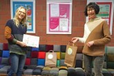 Mit reichlich Abstand übergibt Beate Becker (rechts) vom Kommunalen Integrationszentrum die 'Wortvergnügungstüten' im LEOS an Astrid Bondzio. Foto: Kommunales Integrationszentrum Kreis Lippe