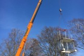 Am Teleskopkran hängt ein Wartehäuschen, bereit für den Aufbau an der Bushaltestelle des Impfzentrums an der Marienfelder Straße. Foto: Kreis Gütersloh