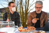 Begeisterung sieht anders aus. Mit seelischer Unterstützung von René Meistell (l.), verspeiste Professor Dr. Carlo Masala (r.) eine Pizza Hawaii. Foto: Christian Weische
