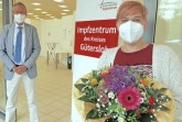 Landrat Sven-Georg Adenauer überreicht Sarah Schuster einen Blumenstrauß. Sie hat die 100.000ste Impfung im Impfzentrum des Kreises Gütersloh erhalten. Foto: Kreis Gütersloh