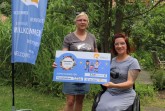 v.l.: Melanie Wiemers und Kati Jördel nehmen den Spendencheck für den Verein Ein Teil vom Ganzen all inklusive entgegen. Jördels nächstes Projekt ist eine Reise mit dem E-Rollstuhl nach Lindau am Bodensee. Für den Strom sorgt das Stadtwerk!