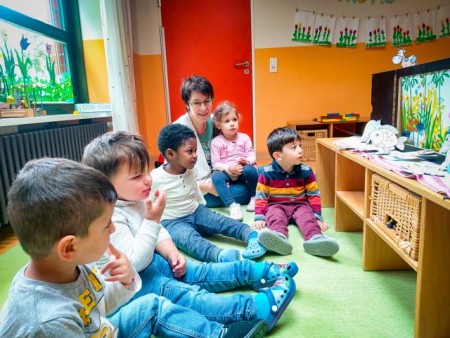  Monika Neroch-Stern mit den Kindern der Käfergruppe vor einem „Kamishibai“ Papiertheater. 