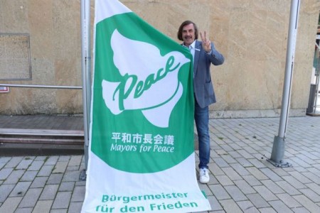 Bürgermeister Norbert Morkes mit der Flagge der "Mayors for Peace" vor dem Gütersloher Rathaus. Foto:Stadt Gütersloh