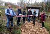 Schnitten gemeinsam das Band zur Einweihung des Bürgerwaldes in Extertal-Bösingfeld durch (v.l.): Manfred Stoller (damaliger Vorsitzender des Umwelt-, Energie- und Betriebsausschuss der Gemeinde), Jörg Düning-Gast (Verbandsvorsteher), Thomas Fritzemeier (Revierförster), Frank Meier (Bürgermeister Extertal), Susanne Hoffmann (Stellv. Leitung Forstabteilung) und Julia Stein (Geschäftsführerin Marketing Extertal e.V.). Foto: Marketing Extertal
