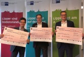 Matthias Carl, stellvertretender Geschäftsführer der IHK Lippe zu Detmold, Thorsten Kost, Abteilungsleiter Firmenkunden Sparkasse Paderborn-Detmold, und Arne Potthoff, Referatsleiter Industrie und Volkswirtschaft bei der IHK Ostwestfalen zu Bielefeld, mit den Sieger-Schecks, die sie Pandemie-bedingt nur virtuell übergeben konnten (v. l.). Foto: IHK Lippe