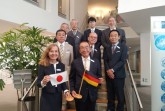 Repräsentieren mit der Flagge des jeweiligen anderen Landes in den Händen die deutsch-japanische Freundschaft: IHK-Hauptgeschäftsführerin Petra Pigerl-Radtke und Yasuto Motomura, Präsident der IHK in Kurume, mit den übrigen Mitgliedern der japanischen Delegation in der IHK in Bielefeld. © JW