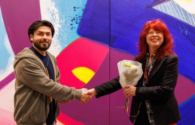 Sayed Aman Sadat aus Afghanistan, der seit vier Jahren in Bielefeld lebt, erhält zum 1.000sten Museumsticket einen Blumenstrauß von Martina Bauer (Atelier Aatifi).Foto: Volker Reinholdt