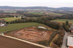 Luftaufnahme der Grabungsfläche für den Neubau des Feuerwehrgerätehauses am Lohagenweg in Hüllhorst. Der Baumbewuchs markiert den Verlauf des Quellbaches, der die Grundlage für die Errichtung der einstigen Hofstelle bildete. Foto: LWL-AfW / A. Koch