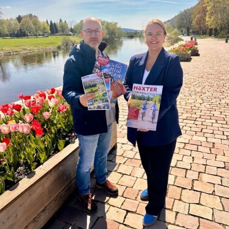 Stephan Berg und Jana Jungblut präsentieren an der Weserpromenade die neuen Printprodukte der Tourist-Information Höxter, die mit frischen Ideen und zielgerichteten Inhalten Lust auf Stadt und die Region machen. Bildquelle: Stadt Höxter