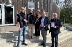 Vor dem Forum Abtei trotzen sie den stürmischen Zeiten: (v.l.) Fotograf und Designer Kalle Noltenhans, Akkordeonist Kamil Dmochowski, Klosterfestival- und Bachwanderung Betreuerin Nicola Nilling, GfW-Geschäftsführer im Kreis Höxter, Michael Stolte, und der künstlerische Leiter der Klosterlandschaft OWL, Hans Hermann Jansen. Foto: Klosterlandschaft OWL/M. Schäfer