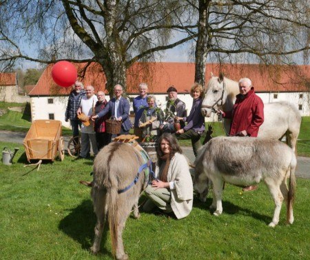 Tatkräftige Vorfreude: (v. l.) Hennes Andree (Stellmacherei), Willi Zacharias (Bäckerei), Hermann Zinser (Brennerei), Dr. Ingo Grabowsky (Museumsdirektor), Elmar Kämper (Mühle), Roswitha Neumann (Weberei), Werner Gerke (Schmiede), Dr. Christiane Wabinski (Referentin Kulturvermittlung), Erwin Borkenhagen (Norikergestüt Borkenhagen) und Elisabeth Bömken stellen beim Pressetermin zum Familientag "Et labora! Handwerk im Kloster" im LWL-Landesmuseum für Klosterkultur ihre Gewerke und Mitmachstationen vor. Mit dabei waren auch die eigensinnigen Eseldamen Rosalie und Lotte. Foto: LWL/Dana Giebken