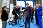 Ein „Energiescouts OWL“-Projekt im Praxistest: Bundeskanzler Friedrich Merz (Mitte), DIHK-Hauptgeschäftsführerin Dr. Helena Melnikov (von rechts) und DIHK-Präsident Peter Adrian lassen sich das Handyladen per Rennrad erläutern von Lui-se Kerker (Auszubildende bei der Dr. Wolff Group/von links), IHK-Projektleiter Benjamin Schattenberg, Alina Schweser (Auszubildende bei der Dr. Wolff Group) und Moritz Harre, Projektlei-ter Energie-Scouts bei der Dr. Wolff Group. Foto: Elena Finke/IHK Ost-Westfalen