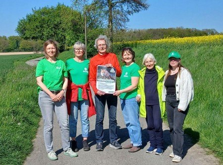 Besonnte und besonnene Fürsprecher:innen des Fuchses: BUND-Aktive beim Treff in Lage-Heßloh mit dem Veranstaltungsplakat, das sowohl in Lemgo als auch in Lage aushängt. Foto: Petra Kuhfus/ BUND Lage.