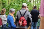 Die Wandergruppe hört gespannt der Wanderführerin Elke Krautscheid zu. Am Rucksack eines Wanderers sieht man die NATUR.PUR-Kette. Foto: pro Wirtschaft GT GmbH