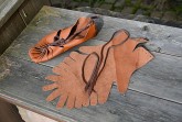 Römische Bundschuhe und zugeschnittene Lederteile auf einer Holzbank
