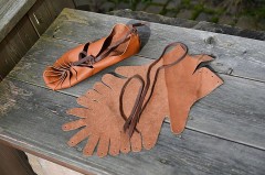Römische Bundschuhe und zugeschnittene Lederteile auf einer Holzbank