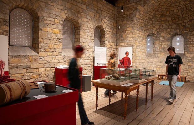 Besucherinnen und Besucher zwischen Vitrinen und Ausstellungsstücken in einem historischen Raum der Kaiserpfalz