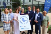 Vertreterinnen und Vertreter aus Politik, Verwaltung und Wirtschaft präsentieren im Kreishaus Gütersloh das Symbol der Laufaktion „Europa Gemeinsam Bewegen“.