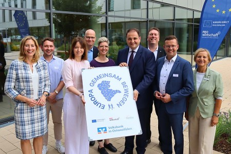 Vertreterinnen und Vertreter aus Politik, Verwaltung und Wirtschaft präsentieren im Kreishaus Gütersloh das Symbol der Laufaktion „Europa Gemeinsam Bewegen“.