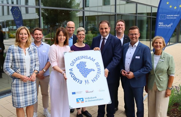 Vertreterinnen und Vertreter aus Politik, Verwaltung und Wirtschaft präsentieren im Kreishaus Gütersloh das Symbol der Laufaktion „Europa Gemeinsam Bewegen“.