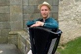 Kamil Dmochowski mit Akkordeon vor einer Steinmauer im Freien