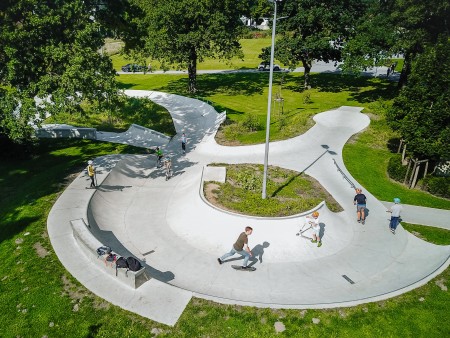 Blick von oben auf den Skatepark in den Almeauen mit Kindern und Jugendlichen auf Skateboards und Tretrollern.