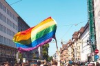 Regenbogenflagge über einer Menschenmenge beim Christopher Street Day in einer Bielefelder Innenstadtstraße.