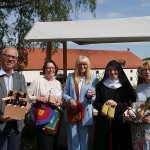 Fünf Personen präsentieren vor dem Kloster Dalheim verschiedene Klosterprodukte, darunter Bier, Handarbeiten, Marmelade und einen Geschenkkorb.