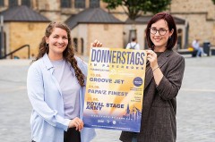 Zwei Frauen halten auf dem Paderborner Domplatz ein Plakat für „Donnerstags in Paderborn“.