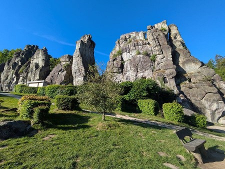 Externsteine bei Horn-Bad Meinberg mit markanten Felsformationen, Grünflächen und Sitzbank unter blauem Himmel