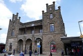 Historisches Empfangsgebäude des Mindener Bahnhofs mit steinerner Fassade und Reisenden vor dem Eingang.