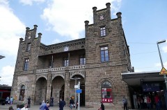 Historisches Empfangsgebäude des Mindener Bahnhofs mit steinerner Fassade und Reisenden vor dem Eingang.